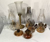 Full view of all 8 hurricane oil lamps showing various sizes, chimneys and brass stands