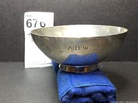 Side view of Tiffany & Co. sterling bowl showing engraved monogram 'A.H.W.' and footed base with slight wear and tarnish.
