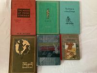 Top view of six vintage children's books arranged side by side showing front covers: The House at Pooh Corner, Now We Are Six, Kindness is a Lot of Things (missing pages), Riley Child Rhymes with Hoosier Pictures, The Pilgrim's Progress, and Little Squirrelie Squirreliekin.