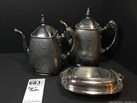 Photo showing all three pieces: tea pot, coffee pot, and covered dish, arranged against a black background.