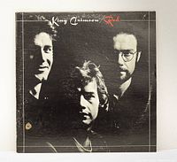 Front cover of King Crimson Red vinyl LP showing three band members with some edge wear.