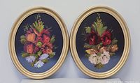 Two oval wood framed floral still-life oil paintings shown side by side against a neutral wall.