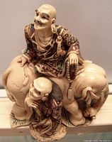 Front and side angled view of the sculpture showing two noblemen figures with patterned robes, one seated on an elephant and one standing beside it, all with detailed facial features and textures.