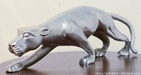 Side view of a silver metal panther statue in a stalking pose showing textured details and matte metallic finish.