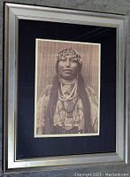 Close-up photo showing detailed view of framed print featuring Native North American woman in traditional jewelry and attire.