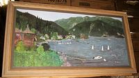 Wide view of framed oil painting showing regatta with sailboats, woody shore, and mountains.