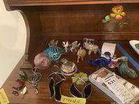 Photo showing collection of animal figurines and metal flowers arranged on wooden surface.