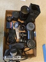 Overview of box with cameras, lenses, lens cases, and accessories