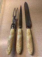 Top view of 3-piece carving set featuring celluloid handles carved with dragon and phoenix designs, showing the metal parts and blades.