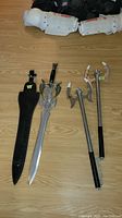 Full view of decorative sword with sheath and pair of chained martial arts weapons on a wooden floor