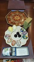 Full lot group featuring enameled eggs on plate, stone-like eggs, coddler in box, and wood tray