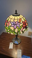 Full view of Tiffany style stained glass table lamp showing floral design on shade and metal base
