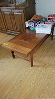 Wide angle view of Lane wood coffee table showing surface wear and placement next to wooden cabinet.
