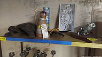 Photo showing metal turtle container, clay bell figure, pewter license plate, and metal bulldog figurine on shelf.