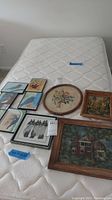 Overview of all seven pieces displayed on a mattress showing frames and art styles including birds and floral needlework