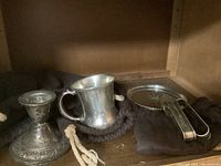 Five-piece sterling silver set arranged on a black felt cloth including candlestick holder, mug, coaster, and two napkin rings.