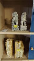 Two carved Foo Dog bookends side by side on a shelf with 7 inch measurement tag