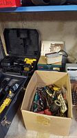 Dewalt drill in open black plastic case with charger, charger cord, and Dewalt battery.