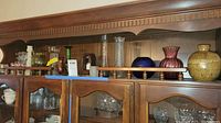 Shelf with vases and candle holders arranged, showcasing size and colors