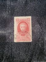 Front view of the antique $5 Centavos red stamp on a dark fabric background, showing the portrait and markings.