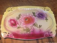 Photo of the antique rectangular plate with pink and purple floral design, showing front face and pattern details.