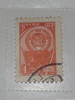 Photo of a vintage 1961 USSR postage stamp in orange-red color with USSR emblem and partial postmark.