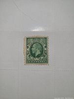 Full view of green half penny postage stamp from England showing King George V profile, perforated edges, and cancellation marks.