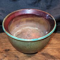 Top view of handmade Raku pottery bowl, showing green exterior and red glazed interior rim