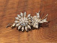 Front view of gold tone floral pin brooch with seed pearl decorations showing some pearls missing and overall detail.