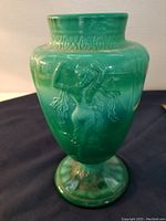 Front view of green art glass vase showing dancing lady relief motif and beaded neck detail.