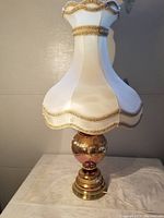 Full view of vintage Bohemian table lamp with white fabric scalloped lampshade and gold trim.