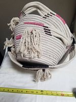 Set of three Indaba woven baskets stacked inside each other on a table with a tape measure showing approximately 14 inches width.