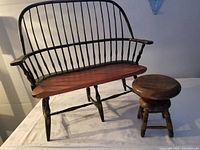 Miniature colonial Windsor barrel back settee bench with spindle-turned legs paired with a miniature wooden round piano stool. Both placed on white cloth background for item display.