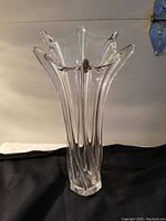 Full view of the large twisted clear Murano glass vase with flared top and petal-like edges on a black cloth background.