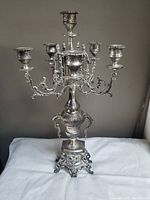 Full view of the ornate silver-tone candelabra showing its design and five candle holders.