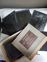 Set of multiple photographic glass plates with some images, placed over a fabric background alongside original cardboard box