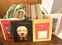 Lot showing all 34 hardback Horizon magazines arranged standing, with three displayed in front showing diverse cover art: red, black, and yellow covers featuring sculpture and abstract art.