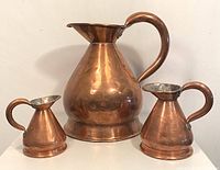 Set of three copper Georgian jugs arranged left to right from smallest to largest