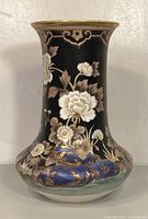 Front view showing black background with white flowers, purple and gold dragon design near base, light green base border and gold accents.