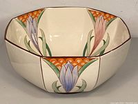 Front view of ceramic Art Nouveau bowl with visible floral hand-painted designs in pastel colors and brown rim.