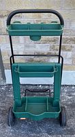 Front view of the green and black folding garden cart with compartments for gardening tools.