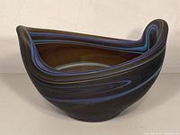 Front and side views of a vintage brown glass bowl with blue spiral patterns, showing its unique shape and color details.