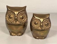 Front view of two brass owl figurines showing eyes and face details