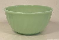 Side view of the light green jadeite mixing bowl showing swirl pattern and rounded rim.