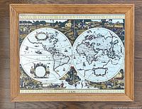 Front view of vintage framed map showing the double hemispheres and wooden frame with clear text title on top and bottom borders.