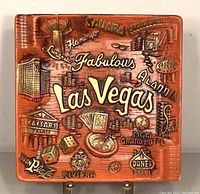 Front view of the square ceramic ashtray showing embossed vintage Las Vegas hotel and casino names and icons with a burnt orange glaze.