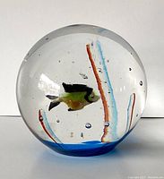 Front view of glass paperweight showing fish and internal chalcedony decorations