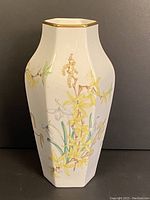 Front view of the vintage hexagonal Wedgwood floral vase with yellow flowers and gold trim.