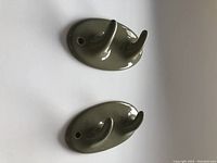 Side angle view of one ceramic dual towel hook showing two curved hooks and mounting holes