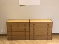 Front view of both oak dressers side by side showing four drawers each